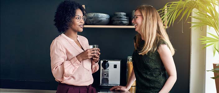 Two women smiling and having a conversation in a break room