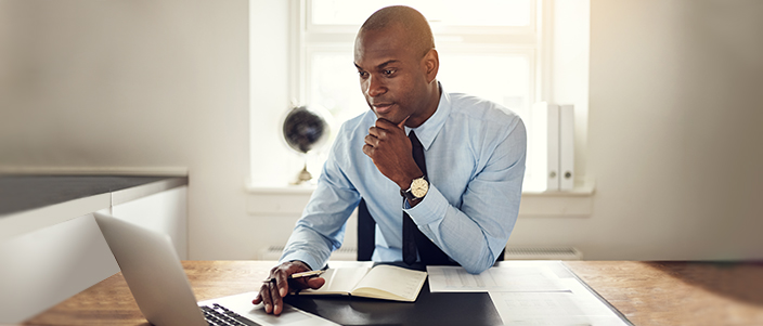 wellness coordinator sitting at desk, looking at his computer thinking about wellness participants