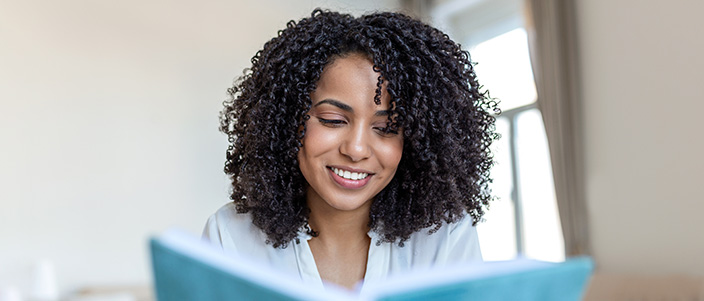 Woman smile while reading a book in at work.