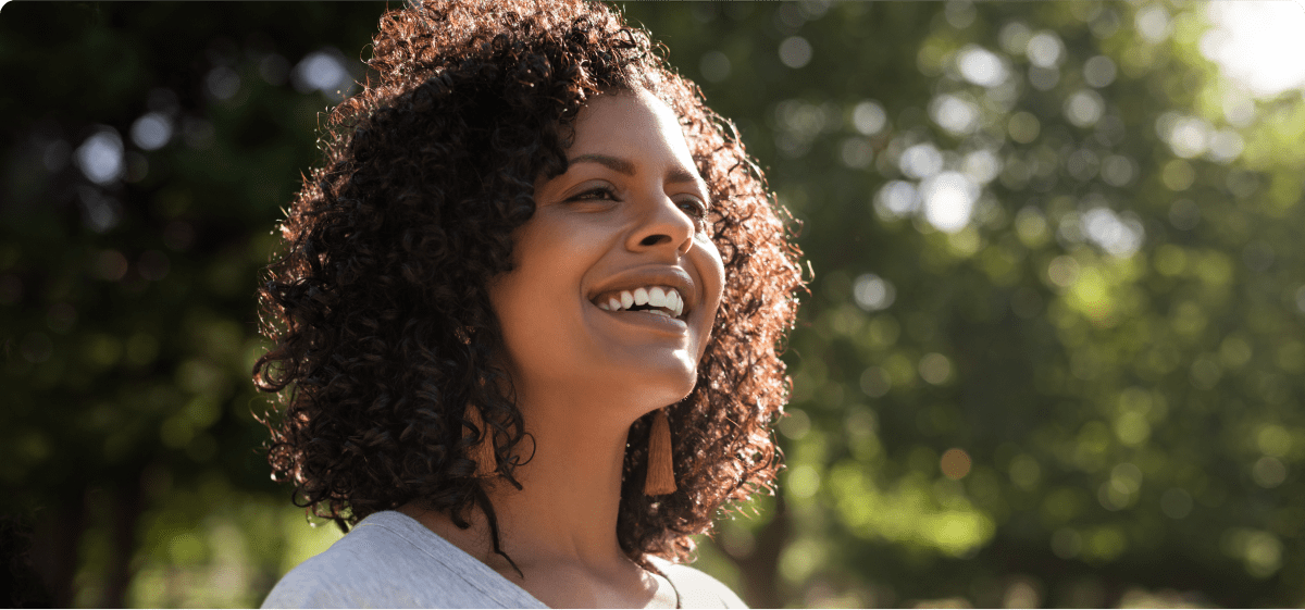 Smiling woman takes a walk outside in the sunshine.