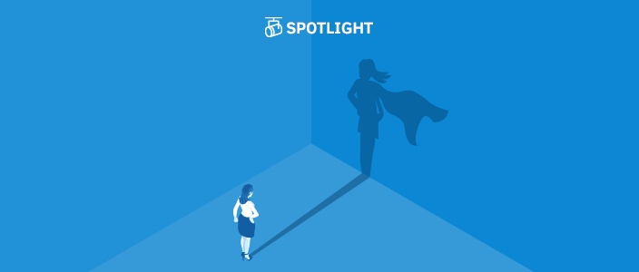 Business woman staring at her shadow on the wall which shows her wearing a cape like a super hero